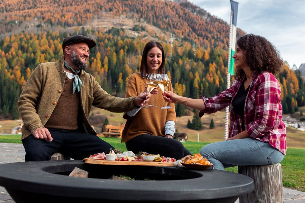 Mangiare e bere in agriturismo in Val di Fassa Gruppo di amici brinda davanti ad un tagliere in un agriturismo in val di Fassa in autunno