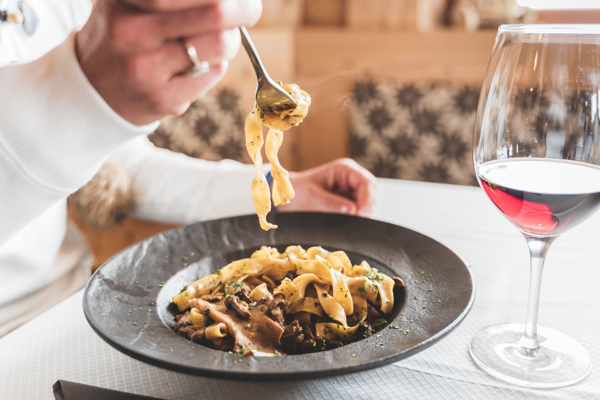 Mangiare al ristorante in Val di Fassa | © Archivio immagini ApT Val di Fassa - Patricia Ramirez Un piatto di tagliatelle ai funghi e un bicchiere | © Archivio immagini ApT Val di Fassa - Patricia Ramirez